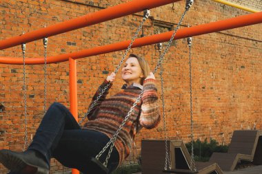 Yaşlı bir kadın yazın şehirde salıncakta sallanıyor..