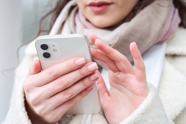 Modern bir akıllı telefondan mesaj yazan kadın ellerinin yakın çekimi. İletişim, teknoloji ve insan kavramı.