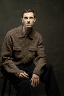 Koyu arkaplanda poz veren şık genç erkek model, moda konsepti.