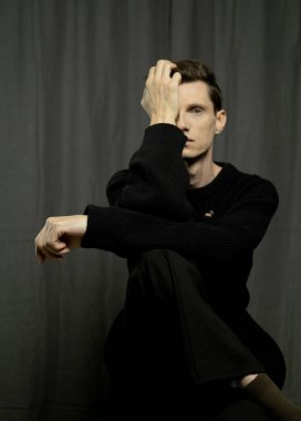 Koyu arkaplanda poz veren şık genç erkek model, moda konsepti.