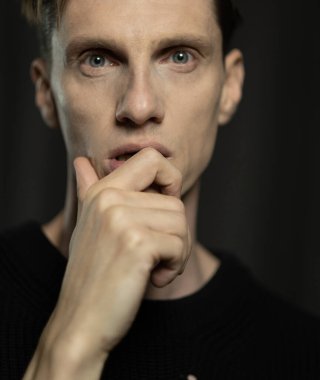 Siyah arka planda poz veren yakışıklı genç adamın yakın plan portresi..