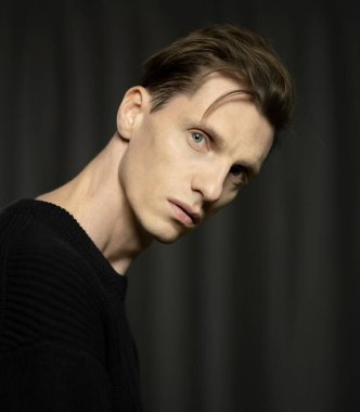 Siyah arka planda poz veren yakışıklı genç adamın yakın plan portresi..