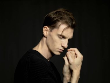 Siyah arka planda poz veren yakışıklı genç adamın yakın plan portresi..