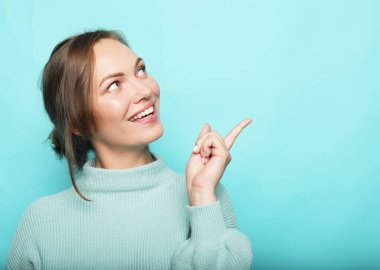 Mutlu gülümseyen güzel genç bir kadın baş parmak işareti gösteriyor.