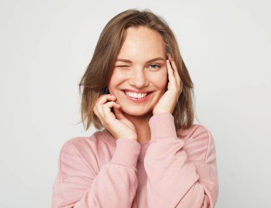 Açık gri arka planda gülümseyen güzel sarışın kadın..