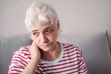 Son sınıf öğrencisinin kanepeye oturması ve evde baş ağrısı çekmesi. Migreni olan yaşlı kadın.