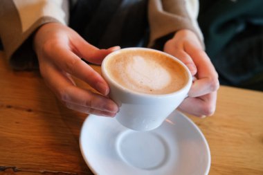 Dolu bir fincan kahve tutuyorum.