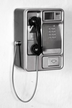 Beyaz bir duvarda ankesörlü telefon