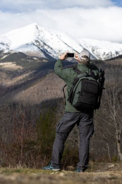 Tanınmayan turist, kışın İspanyol Pirenesi Dağı 'nda cep telefonuyla fotoğraf çekiyor.