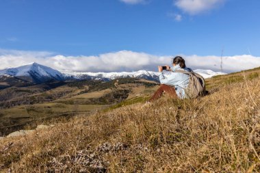 İspanyol turist kadın oturuyor ve cep telefonuyla resim çekiyor kışın İspanyol Pirenesi Dağı 'nda