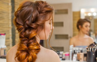 Güzel, uzun, Kızıl saçlı kızla Kuaför bir Fransız örgü, bir güzellik salonu örgüleri. Profesyonel saç bakımı ve saç modelleri oluşturma.
