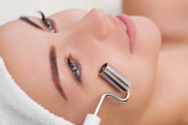 Kozmetik uzmanı bu aleti güzellik salonundaki genç ve güzel bir kadının mikro-akım terapisi için bir prosedür haline getiriyor. Kozmetoloji ve profesyonel cilt bakımı.