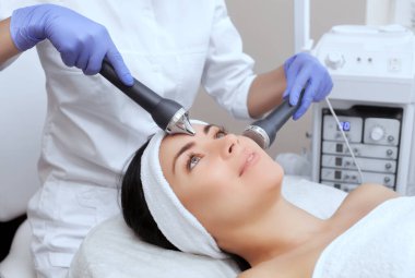 Kozmetik uzmanı bu işlemi güzellik salonundaki güzel, genç bir kadının yüz derisini ultrasonik olarak temizliyor. Kozmetoloji ve profesyonel cilt bakımı..