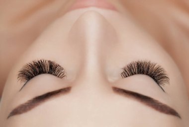 Kirpik uzatma prosedürünü kapat. Güzellik salonunda uzun kirpikleri olan güzel bir kadın.