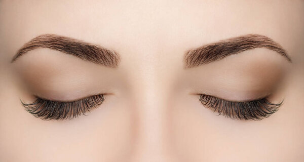 Beautiful Woman with long lashes in a beauty salon. Eyelash extension procedure.
