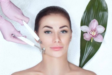 Kozmetik uzmanı bu aleti güzellik salonundaki genç ve güzel bir kadının mikro-akım terapisi için bir prosedür haline getiriyor. Kozmetoloji ve profesyonel cilt bakımı.