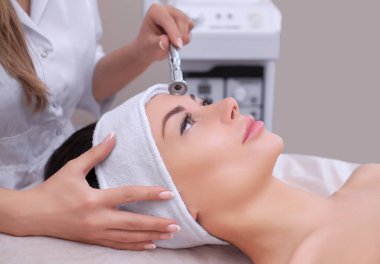 Kozmetik uzmanı, güzellik salonundaki güzel, genç bir kadının yüz derisinin mikro cilt bakımını yapıyor. Kozmetoloji ve profesyonel cilt bakımı..