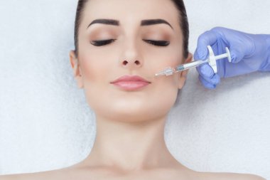 The doctor cosmetologistbotox injection on the lips of a beautiful woman in a beauty salon.Cosmetology skin care. clipart