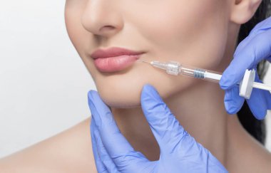 The doctor cosmetologist makes Lip augmentation procedure of a beautiful woman in a beauty salon.Cosmetology skin care. clipart