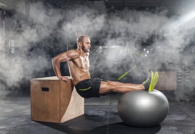 Vücut geliştirici, egzersizleri spor salonunda fitness topuyla yapıyor. Spor konsepti, yağ yakma ve sağlıklı bir yaşam tarzı..