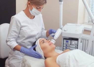 Kozmetik uzmanı, güzellik salonundaki genç ve güzel bir kadının yumuşak fırçasıyla Hırdavat yüz temizleme prosedürünü gerçekleştiriyor. Kozmetoloji ve profesyonel cilt bakımı.