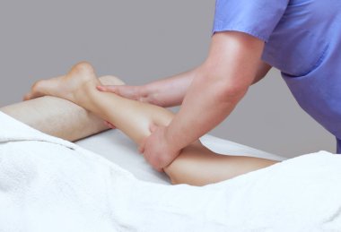 Doktor-ayak hastalıkları uzmanı hastanın bacaklarına muayene ve masaj yapar.