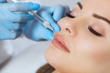 Doktor kozmetik uzmanı güzellik salonunda güzel bir kadının dudak büyütme prosedürünü yapıyor. Kozmetik cilt bakımı..