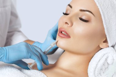 Doktor kozmetik uzmanı güzellik salonunda güzel bir kadının dudak büyütme prosedürünü yapıyor. Kozmetik cilt bakımı..