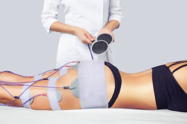 Güzellik salonundaki bir kadının bacaklarında ve kalçalarında miostimülasyon prosedürü. Vücuda özen göstermek, aşırı ağırlığı azaltmak..