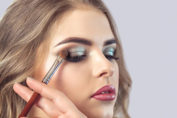 Makeup artist makes smoky eyes makeup. Applying make-up and face care.