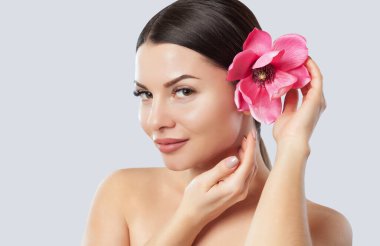 Güzel makyajlı bir kadının portresi elinde bir Manolya çiçeği tutuyor. Profesyonel makyaj ve cilt bakımı.