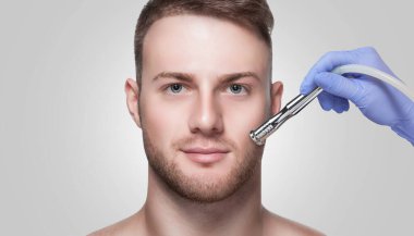 Bir kozmetikçi, güzellik salonunda yüz derisinin mikro cilt bakımını yapıyor. Erkekler için kozmetoloji ve profesyonel cilt bakımı.