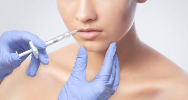 Bir kozmetolog güzellik salonundaki Lips büyütme prosedürünü uyguluyor. Kozmetoloji cilt bakımı..
