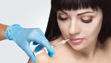 Doktor kozmetik uzmanı güzellik salonunda güzel bir kadının dudak büyütme prosedürünü yapıyor. Kozmetik cilt bakımı..