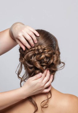 Güzel, şehvetli, açık kahverengi saçlı bir kadının portresi. Bir güzellik salonunda düğün saç stili. Saç stilini kuaför yapıyor. Düğün saç stili.