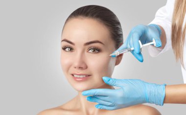 Doktor kozmetik uzmanı güzellik salonundaki güzel bir kadının cildindeki kırışıklıkları sıkmak ve düzleştirmek için canlandırıcı enjeksiyon prosedürü uyguluyor..