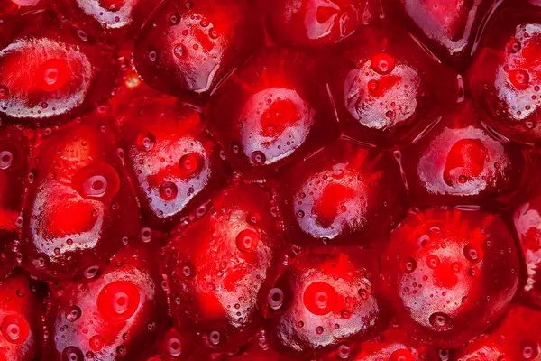Macro slices of pomegranate fruit with drops of water on grains.