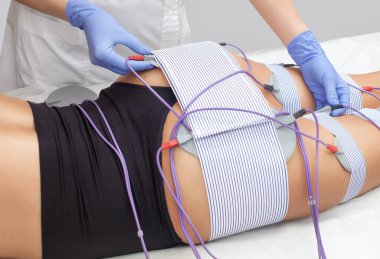 Güzellik salonundaki bir kadının bacaklarında ve kalçalarında miostimülasyon prosedürü. Aşırı kilolu tedavi. Kozmetoloji ve masaj konsepti.