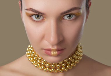 Güzel, mutlu bir kadının portresi. Güzel, yaratıcı, altın renkli bir makyajı var. Boynunda altın boncuklar var. Makyaj konsepti.