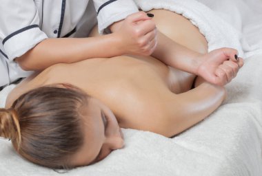 Masör, kaplıcadaki genç ve güzel bir kadının boynuna, omuzlarına ve sırtına rahatlatıcı bir masaj yapar. Kozmetoloji ve masaj konsepti.