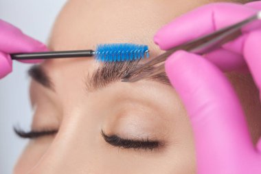 Makyöz, kaşlarını cımbızla kazıyarak bir kadına kına sürmeden önce makyaj konsepti, kaş şekilli modelleme ve kirpik uzatma yapar..