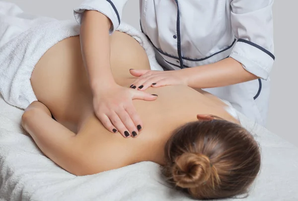 Masseur makes a relaxing massage on the neck, shoulders, back and collarbones of a young beautiful woman in a spa. Cosmetology and massage concept.