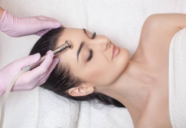 Kozmetik uzmanı, güzellik salonundaki güzel bir kadının yüzünün mikro cilt bakımını yapıyor. Kozmetoloji ve profesyonel cilt bakımı..