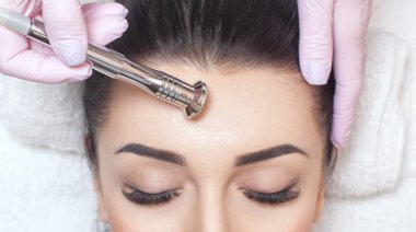 Kozmetik uzmanı, güzellik salonundaki güzel bir kadının yüzünün mikro cilt bakımını yapıyor. Kozmetoloji ve profesyonel cilt bakımı..