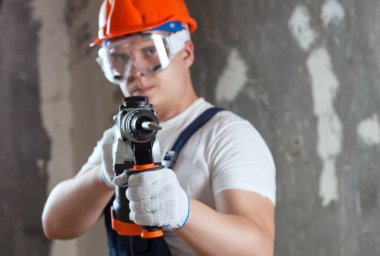 Çekiç delici ekipmanlı müteahhit inşaat alanında duvarda delik açıyor. Tamir işleri, duvarların iç dekorasyonu..