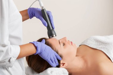 Kozmetik uzmanı bu işlemi güzellik salonundaki güzel, genç bir kadının yüz derisini ultrasonik olarak temizliyor. Kozmetoloji ve profesyonel cilt bakımı..