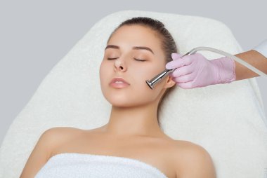 Kozmetik uzmanı, güzellik salonundaki güzel bir kadının yüzünün mikro cilt bakımını yapıyor. Kozmetoloji ve profesyonel cilt bakımı..