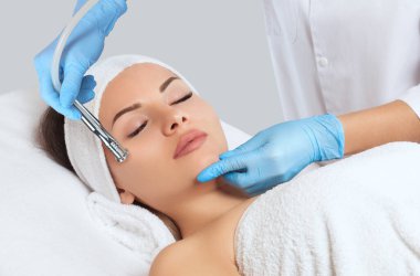Kozmetik uzmanı, güzellik salonundaki güzel bir kadının yüzünün mikro cilt bakımını yapıyor. Kozmetoloji ve profesyonel cilt bakımı..