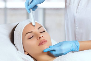 Kozmetik uzmanı Couperose tedavisi uygular ve güzellik salonundaki genç ve güzel bir kadının cildinin temizlenmesi ile yüzleşir. Kozmetoloji ve profesyonel cilt bakımı..