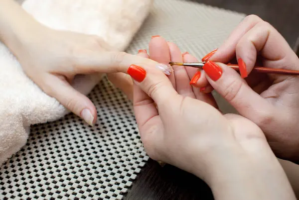 The master of the manicure attaches a nail shape during the procedure of nail extensions with gel in the beauty salon. Professional care for hands.